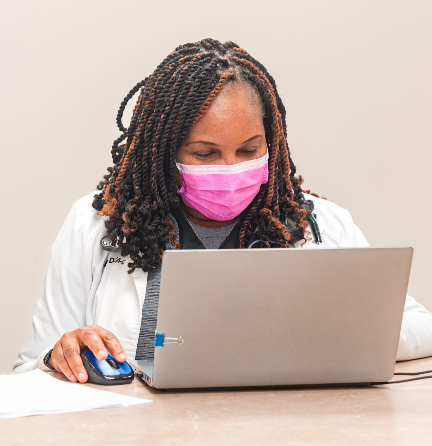 MPCP Provider with a mask logging into a computer for a telemedicine appointment